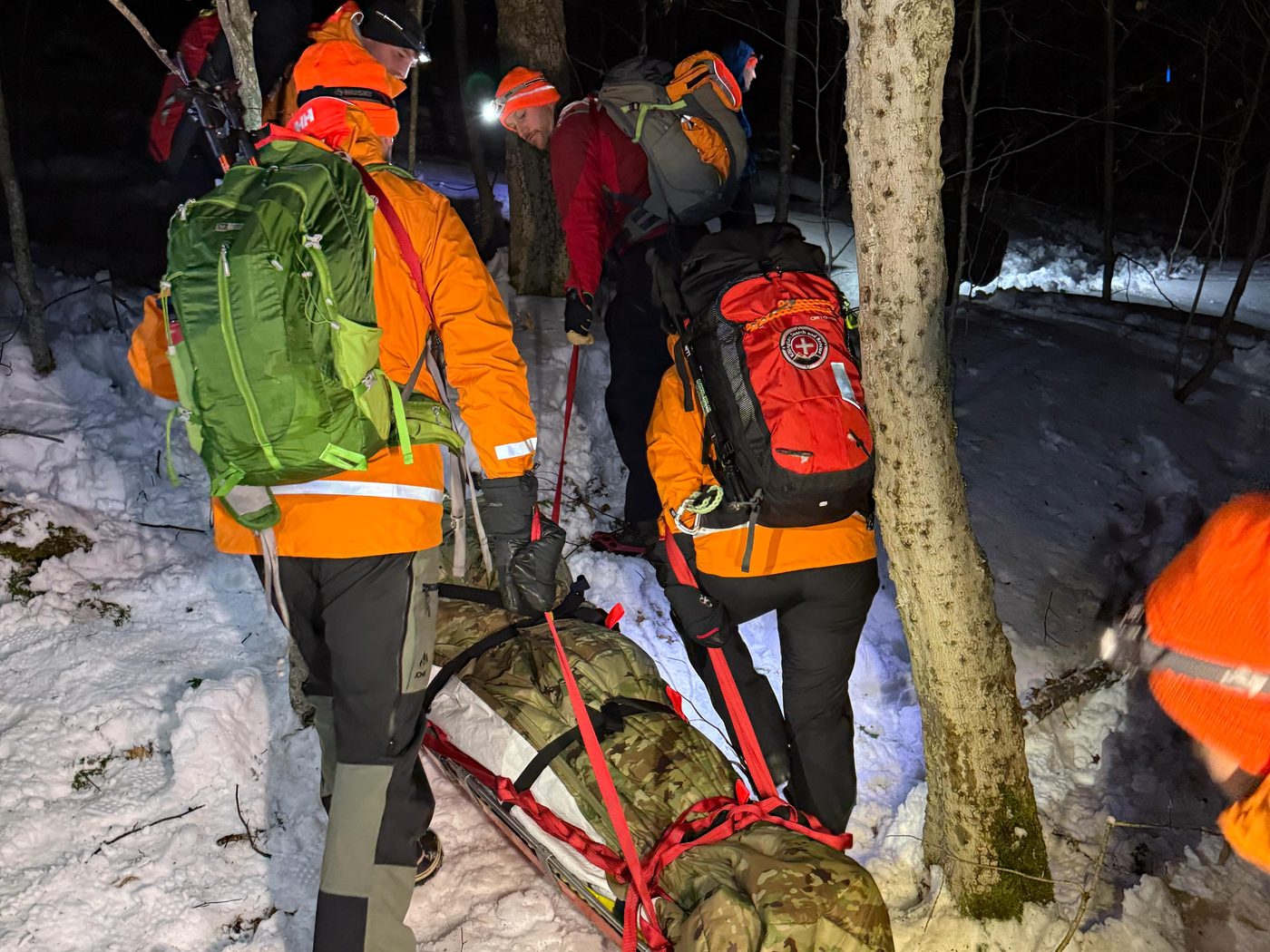 KSAR members haul a litter with a volunteer patient up a snowy trail in the dark