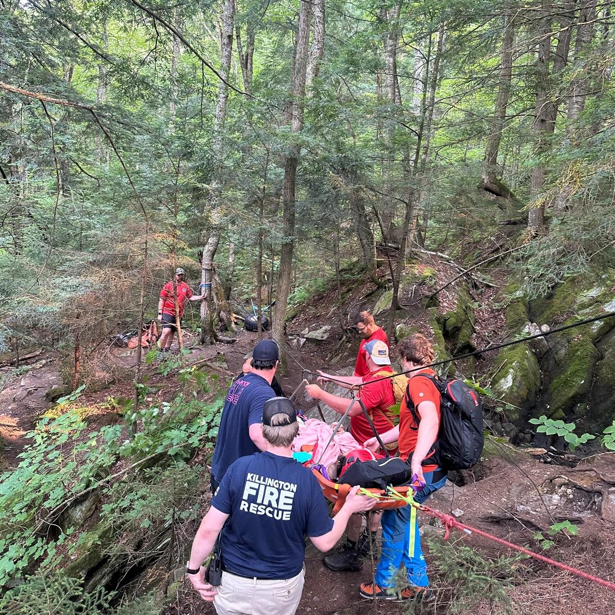 KSAR and Killington Fire Rescue crews carry a patient in a litter down a wooded trail